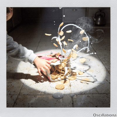 Dramatic Instax freeze-frame of child's hand in sweater spilling golden cornflakes from p…