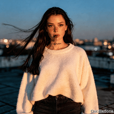 Freckled woman with wind-swept hair and hazel eyes in knit sweater on dusk rooftop has bl…